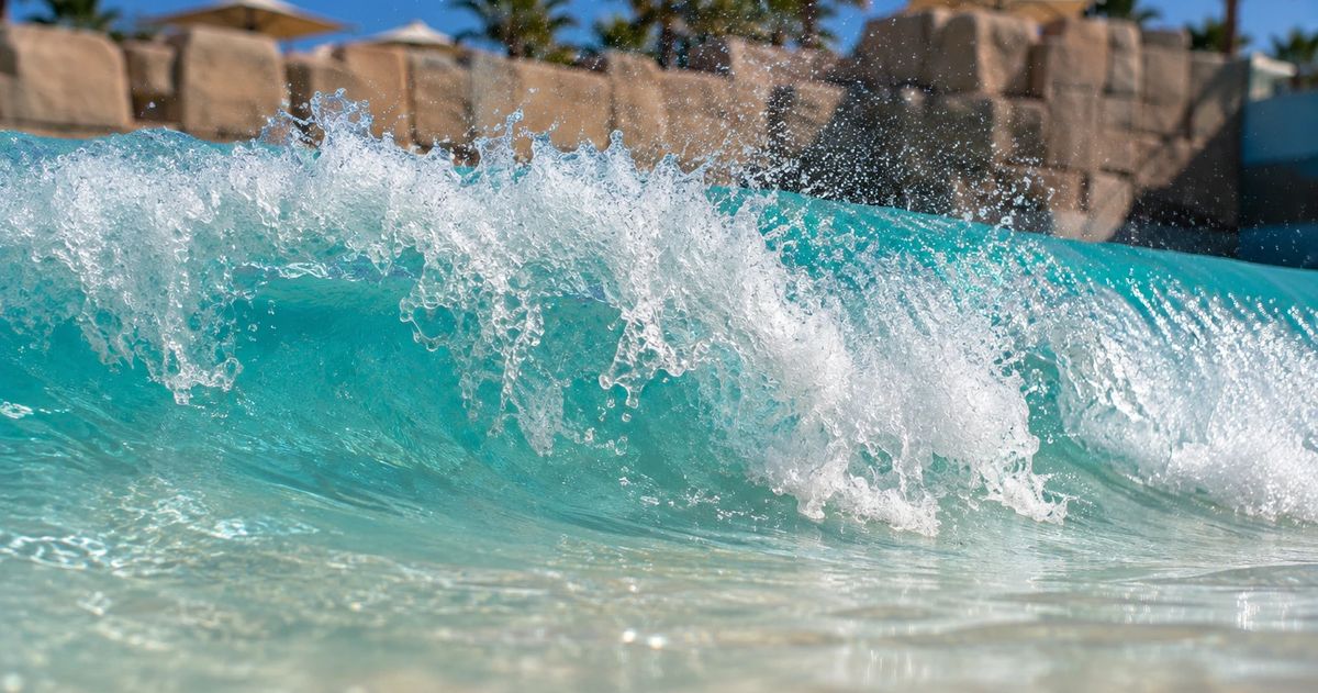 Wave breaking across the shallow beach entry of a commercial wave pool
